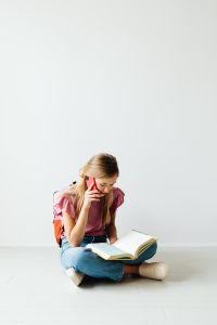 Young girl uses phone and reads a book