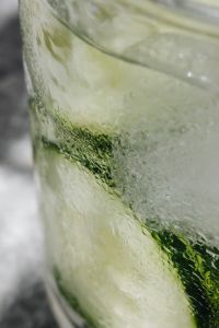 Water glass - cucumber - ice cubes - marble - closeup - close-up - close up