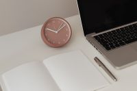 Kaboompics - Detail of desk with laptop - supplies - notepad - clock - time - pen