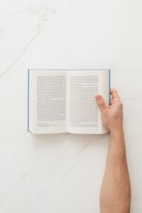 Kaboompics - Hand holding open book on marble table