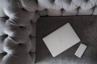 Kaboompics - Silver laptop and an iPhone on a grey sofa