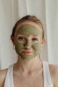 Young Woman Applying Green Clay Mask to Her Face