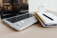 Kaboompics - Laptop - compter - desk - glass of water - Macbook - AirPods - Earphones - Notebook - Pen