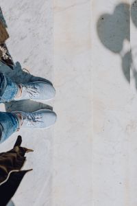 A woman dressed in blue jeans and sneakers is standing on a white marble staircase