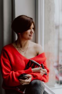 Kaboompics - A woman in a red sweater does her make-up - applies a foundation with a brush