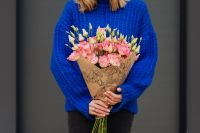 Kaboompics - Close up of woman holding bouquet of pink lisianthus flowers wrapped in brown paper