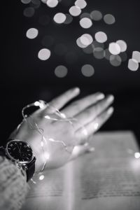 Female hand, fairy lights, book