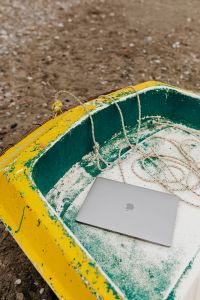 Kaboompics - Macbook laptop on a small yellow boat on the beach