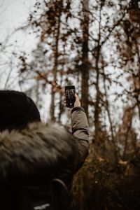 Kaboompics - A woman takes a picture with her iPhone X in the autumn forest