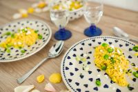 Yellow rice with greens on a cute plate with blue hearts and a table decorated with flower petals
