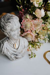 Gold jewellery in white marble - flowers and a small sculpture, a shell