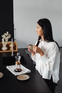Kaboompics - An adult young Asian woman pours coffee into a cup from a Chemex