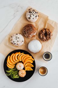 Donuts, coffee & plate with fruits: orange, madarine, kiwi
