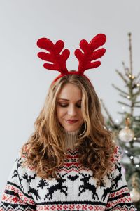 Kaboompics - The woman in the Christmas sweater and reindeer horns on her head
