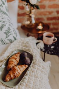 Croissants and figs on a green plate, a cup of coffee and a candle
