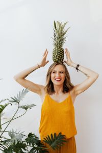 Kaboompics - A beautiful smiling young woman is holding a pineapple