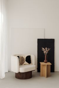 A cozy cream-colored armchair placed next to minimalist black and white artwork with a small side table adorned with natural objects