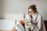 Kaboompics - Cocooning - isolating yourself - staying at home - a woman under a blanket - putting on glasses - reading book