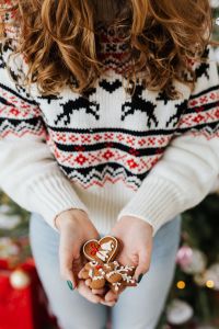The woman in the Christmas sweater holds gingerbread