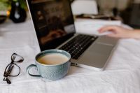 Kaboompics - A woman works at a desk with a laptop and a cup of coffee