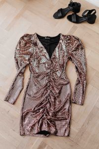 gold rose sequin dresses and boots lie on a wooden parquet,