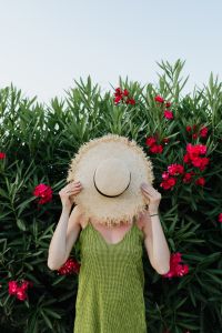Kaboompics - A smiling woman in a summer hat with pink flowers