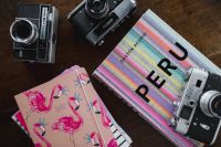 Old analog cameras and pink books on a wooden table