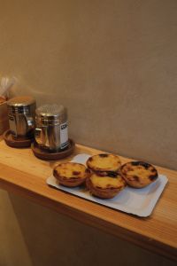 Kaboompics - Pastel de Nata on a Rustic Wooden Counter in a Cozy Cafe