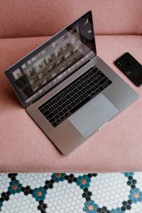 MacBook Pro laptop & iPhone X mobile on a pink sofa