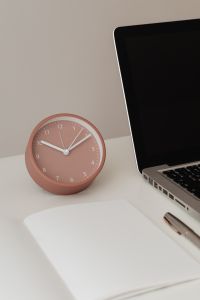 Kaboompics - Detail of desk with laptop - supplies - notepad - clock - time - pen