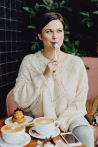 Kaboompics - A woman drinks coffee and eats a dessert in a café