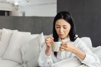 Kaboompics - A young Asian woman relaxes on the couch and drinks coffee or tea