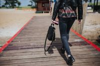 Kaboompics - Woman with a black bag and a can of coke walking on a wooden pier
