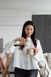 Kaboompics - An Asian adult woman pours coffee from a Chemex into a cup