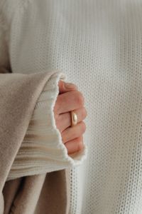 Woman in white sweater - gold rings - jewelry - beige wool jacket
