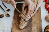 Kaboompics - Woman is cutting bread on cutting board