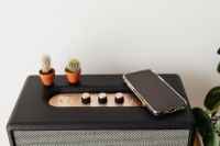 Black speaker on marble table, white wall, mobile phone, cacstus