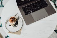 Working with a laptop, meringue with whipped cream on white marble
