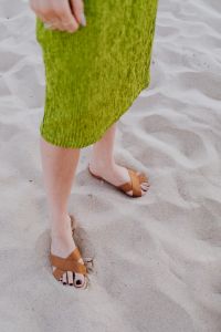 A woman in a green dress and leather shoes on sand