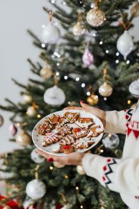 Kaboompics - Woman in a white Christmas sweater holds gingerbread cookies on plate