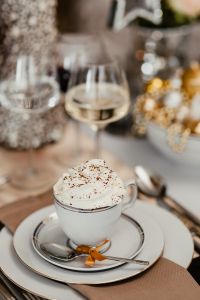 Coffee with whipped cream in a porcelain cup on a Christmas table