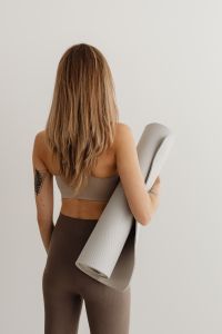Young adult woman - yoga mat - brown leggings - exercise outfit