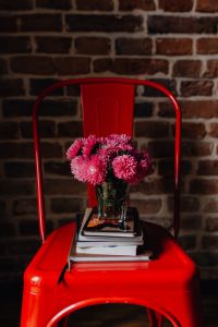 Industrial metal chair with a bouquet of pink flowers and books on it