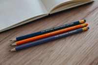 Kaboompics - Notebook with colourful pencils on a wooden desk