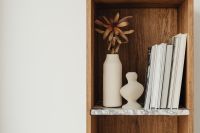 Kaboompics - Books on a bookcase - marble shelves - vase - dried flower
