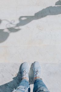A woman dressed in blue jeans and sneakers is standing on a white marble staircase