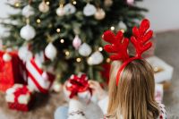 Kaboompics - Woman Wearing Reindeer Horns on Head, Wrapping Gift, Christmas Tree Background