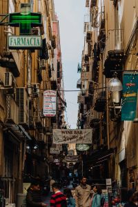 Narrow street with shop and restaurant signs in Naples