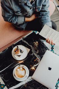 Kaboompics - MacBook laptop, coffee and cake with meringue and whipped cream on black marble