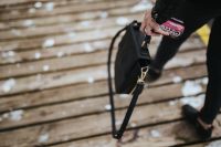 Kaboompics - Woman with a black bag and a can of coke walking on a wooden pier